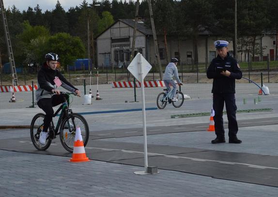 policjant sprawdza umiejętności młodego rowerzysty na torze